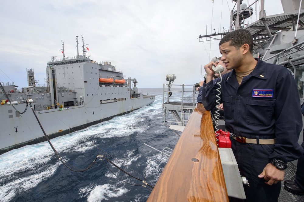USS Barry (DDG 52) Sailor communicates with USNS Cesar Chavez (T-AKE-14) during replenishment at sea (RAS) with USS Antietam (CG 54)