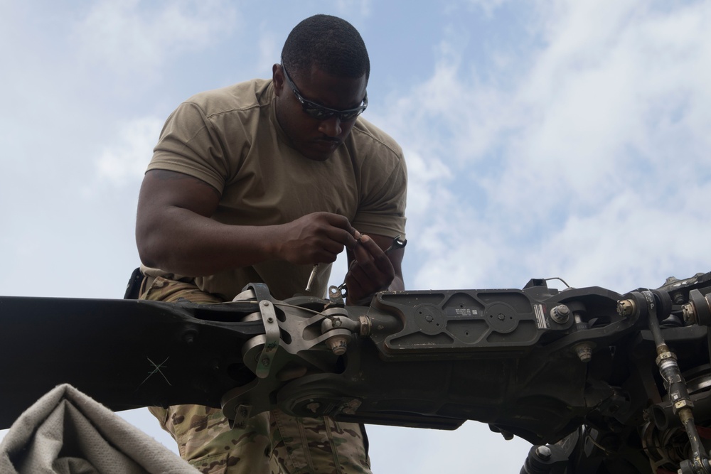 Spc. Kendall Smith removes a bolt from the main rotor housing of an AH-64D Apache Longbow helicopter.