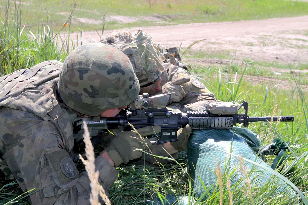 U.S. Army soldier instructs Polish Army soldier on range estimation