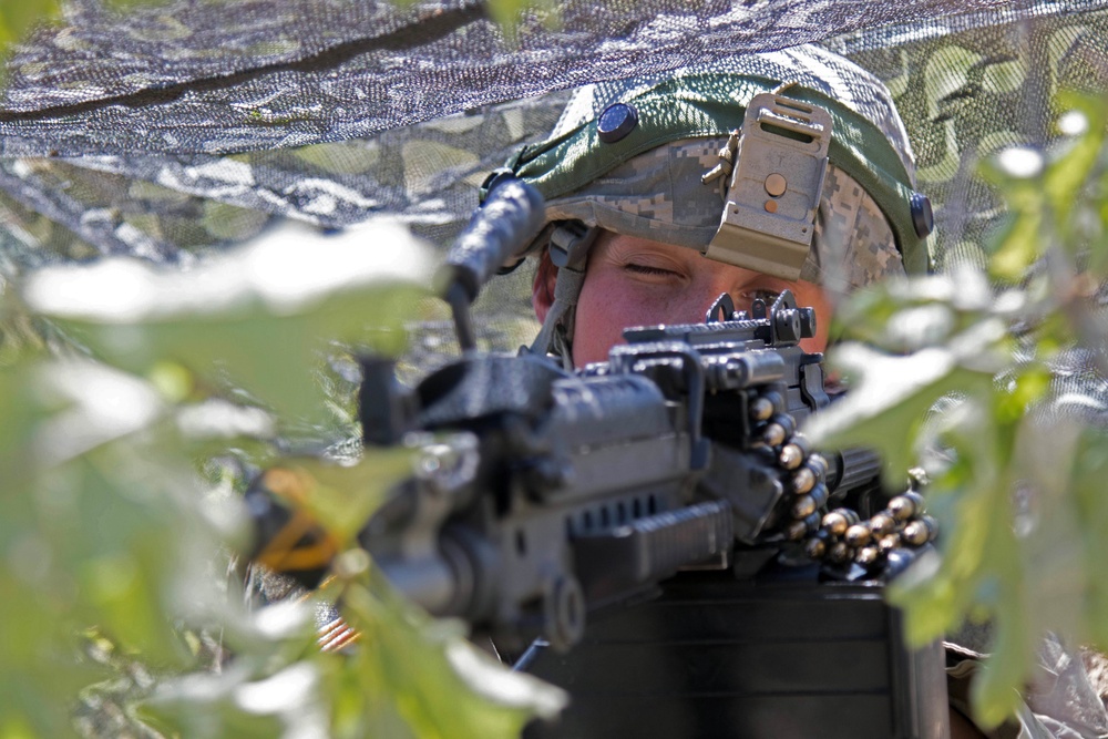 Soldier watches over perimeter in a foxhole during Combined Arms Exercise