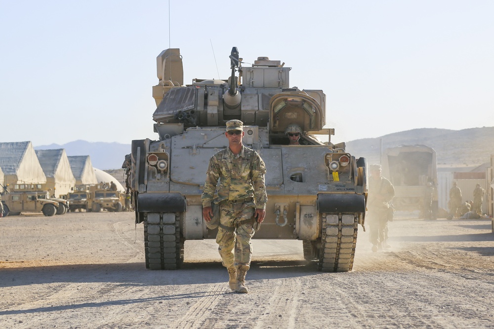 A U.S. Army Soldier assigned to 3rd Armored Brigade Combat Team, 1st Armored Division, Fort Bliss, Texas, ground guides an M2 Bradley Infantry Fighting Vehicle