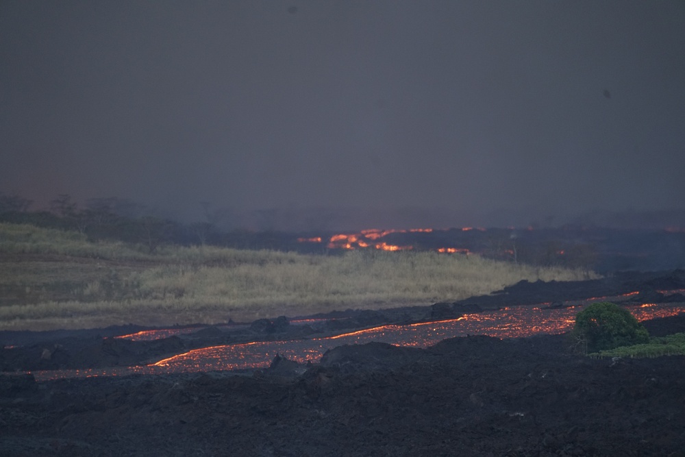 River of lava flows down valley in Hawaii.