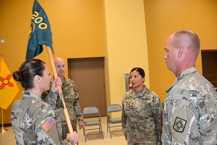 Capt. Erin Montoya, outgoing commander of the 200th Public Affairs Detachment, 93rd Troop Command, New Mexico Army National Guard, prepares to hand over the unit colors to Col. Michael A. Treadwell.