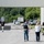 The image depicts a law enforcement operation at what appears to be an industrial or warehouse facility. Multiple agents are visible, including personnel wearing tactical vests marked 'POLICE' and 'HSI' (Homeland Security Investigations). The scene suggests an active federal law enforcement action such as a raid or enforcement operation.