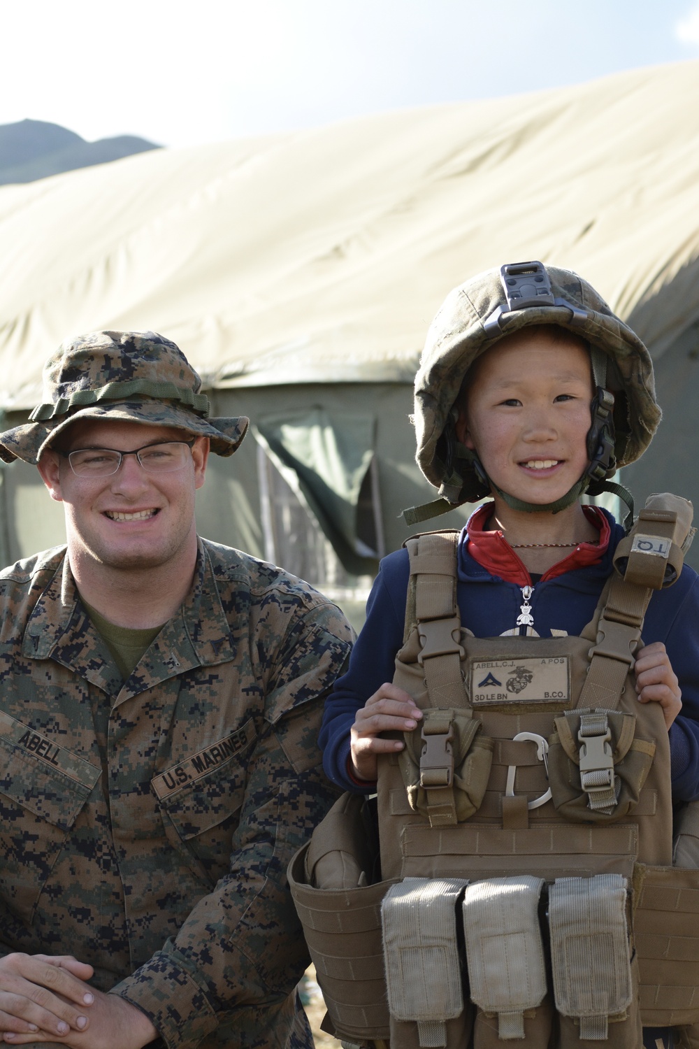 U.S. Marine Lance Cpl. Corbin Abell, military policeman, 3rd Law Enforcement Battalion, III Marine Expeditionary Force, allows a Mongolian child to try on his kevlar and flak vest.