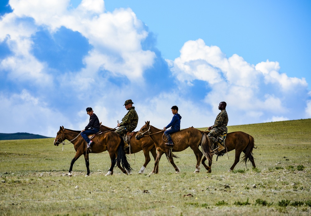 Marines ride with Mongolian children.