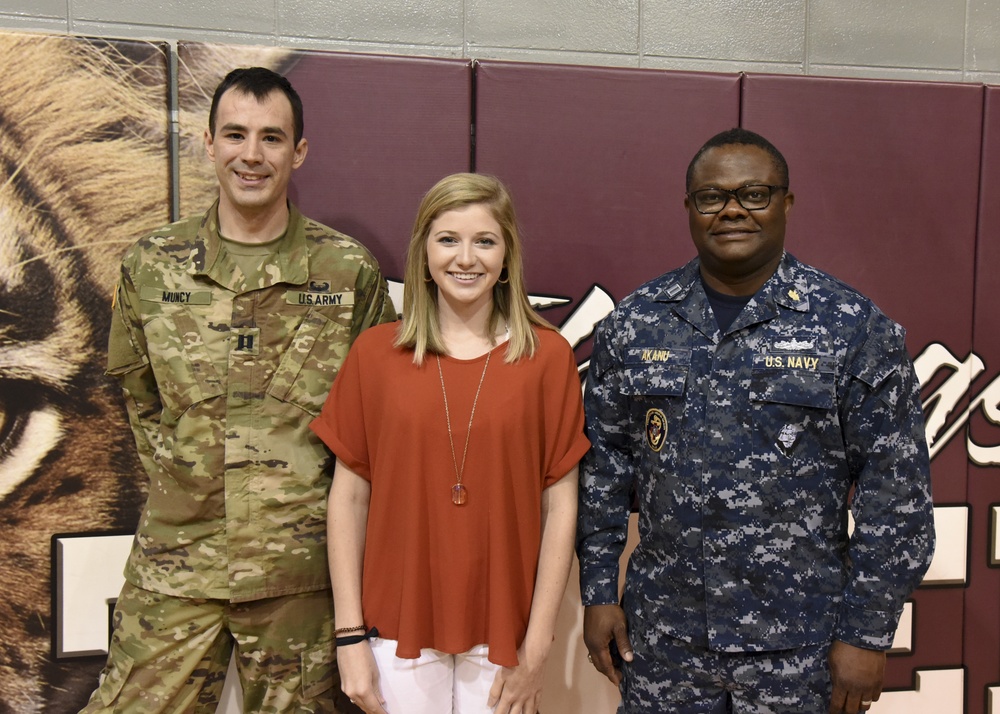 Service member pose for photo with student who sang National Anthem