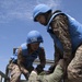 Two Mongolian Armed Forces members representing the United Nation lift simulated injured U.S. Marine.
