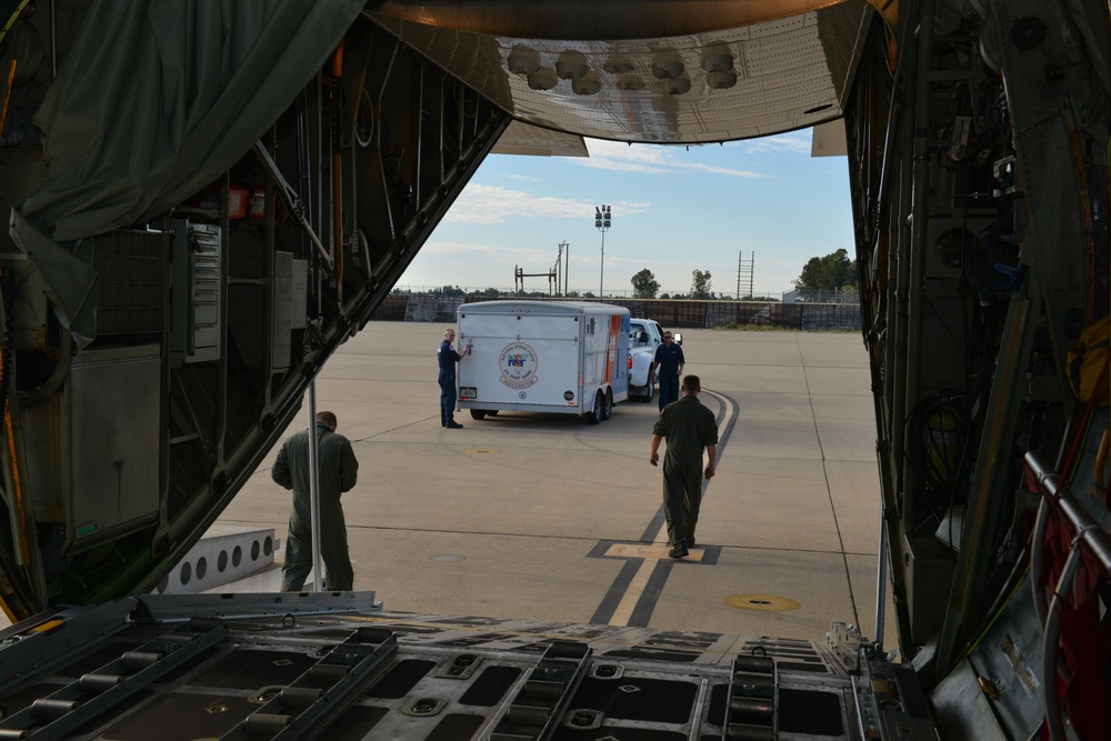 Coast Guard Pacific Strike team members and an Air Station Barbers point aircrew load decontamination gear for RIMPAC exercise