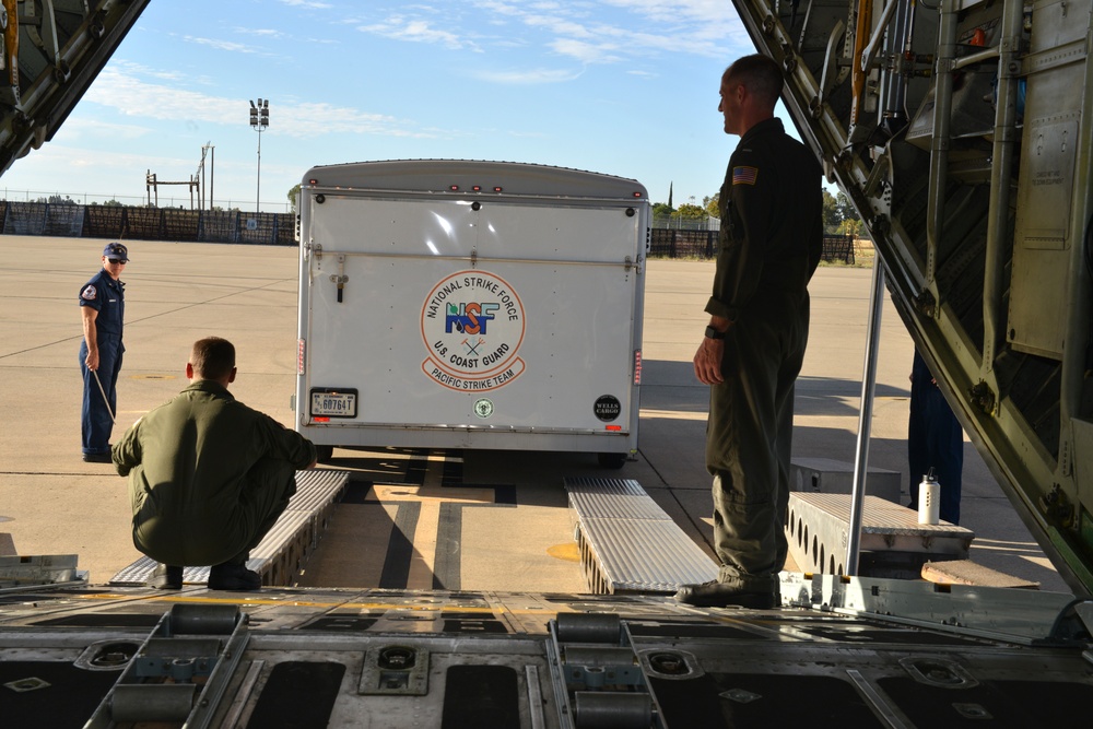 Coast Guard Pacific Strike team members and an Air Station Barbers point aircrew load decontamination gear for RIMPAC exercise