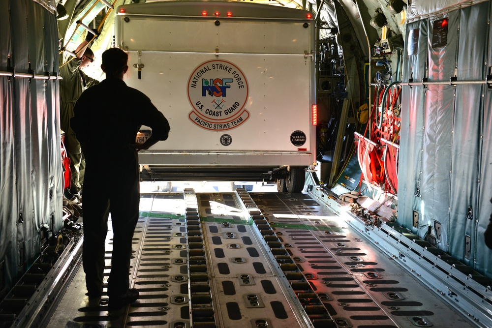 Coast Guard Pacific Strike team members and an Air Station Barbers point aircrew load decontamination gear for RIMPAC exercise