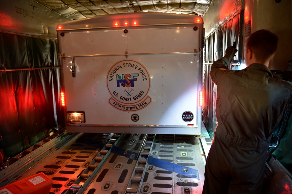 Coast Guard Pacific Strike team members and an Air Station Barbers point aircrew load decontamination gear for RIMPAC exercise