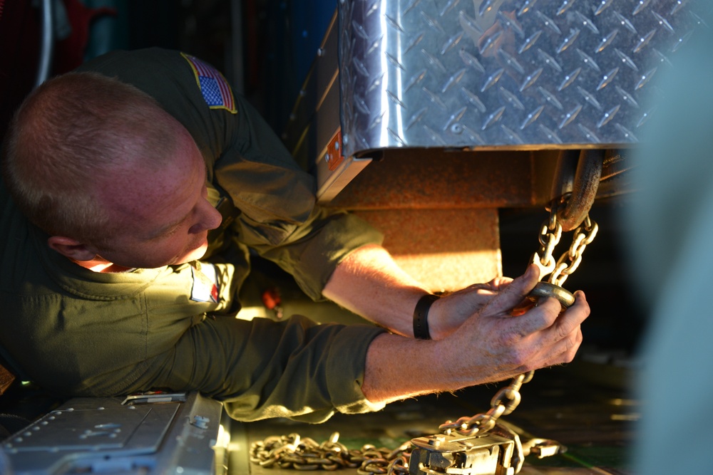 Coast Guard Pacific Strike team members and an Air Station Barbers point aircrew load decontamination gear for RIMPAC exercise