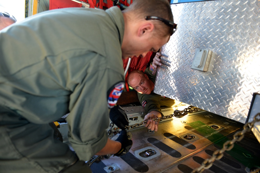 Coast Guard Pacific Strike team members and an Air Station Barbers point aircrew load decontamination gear for RIMPAC exercise