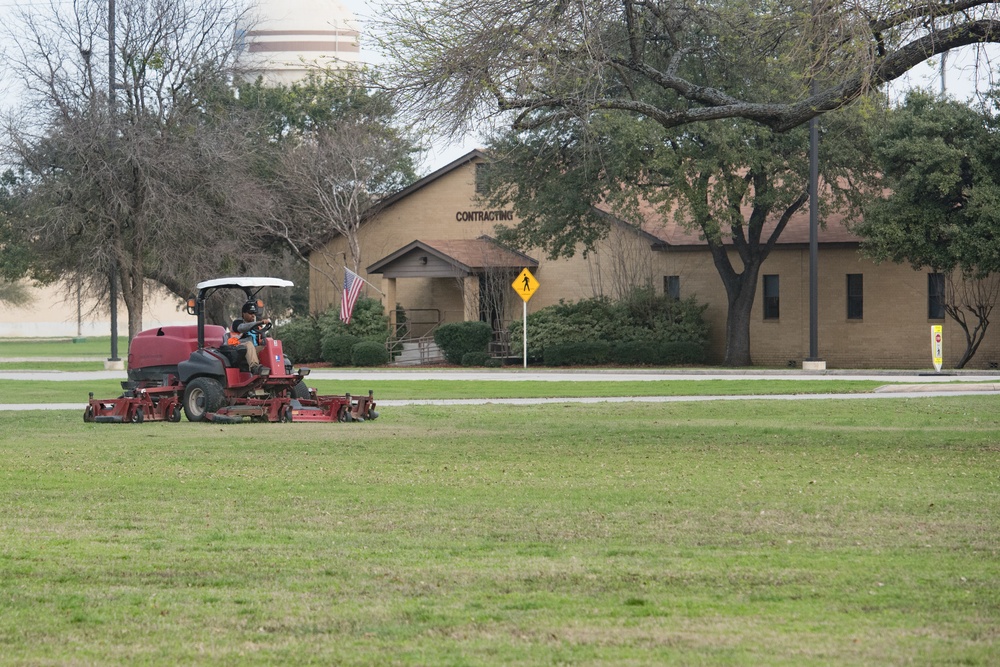 JBSA-Lackland Grounds Maintenance worker cutting grass in field