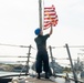 A Sailor lowers the Jack as USS Preble (DDG 88) gets underway for the at sea phase during RIMPAC