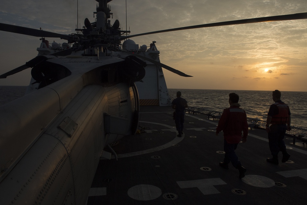 USCGC Bertholf crew clears the flight deck for arrive al US Navy HSC-6 helicopter