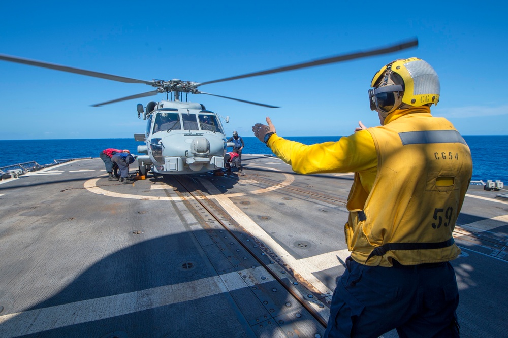 USS Antietam (CG 54) Sailor signals to a MH-60R Sea Hawk helicopter from the “Warlords” of HSM 51