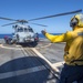 USS Antietam (CG 54) Sailor signals to a MH-60R Sea Hawk helicopter from the “Warlords” of HSM 51