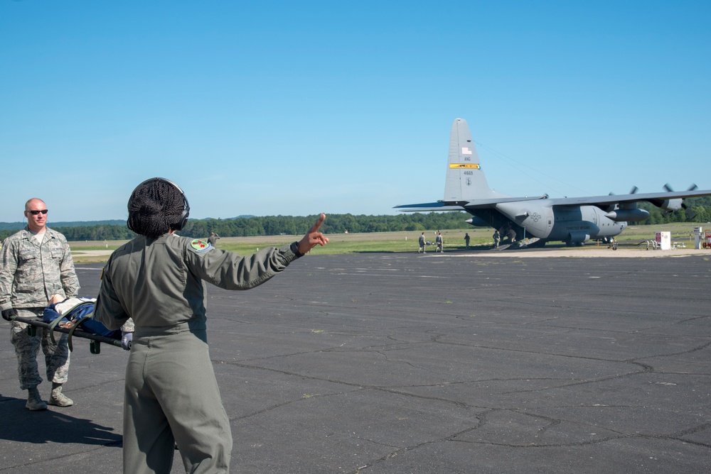 A flight medic provides direction on loading a C-130 Hercules with patients