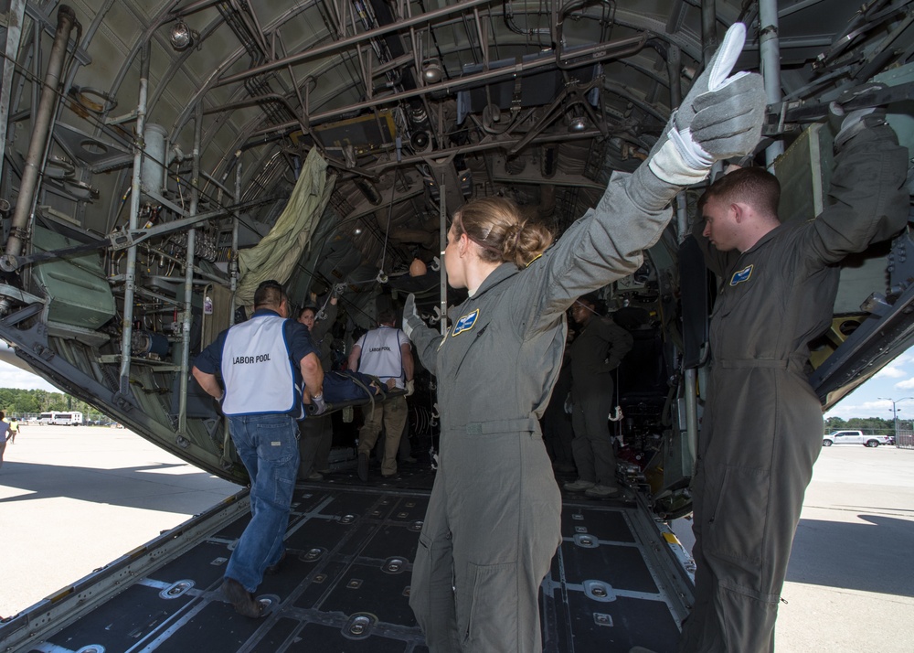 A flight medic provides direction on loading a C-130 Hercules with patients