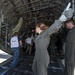 A flight medic provides direction on loading a C-130 Hercules with patients