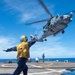 USS Antietam (CG 54) Sailor signals to MH-60R Sea Hawk during an in-flight refueling