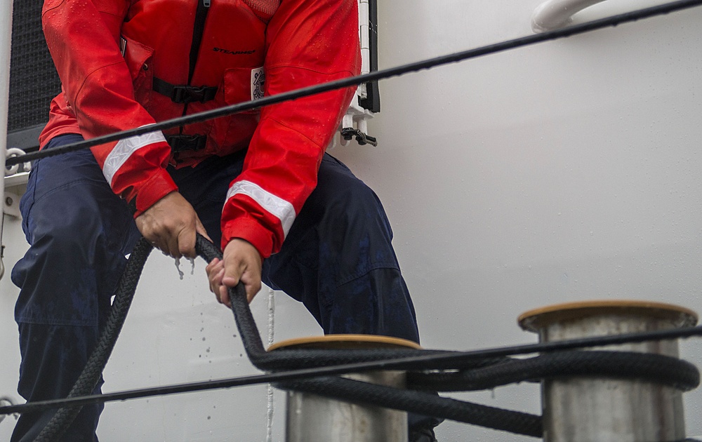 Coast Guard crew member secures a line to set of bitts