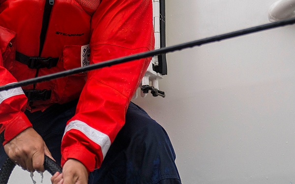 Coast Guard crew member secures a line to set of bitts