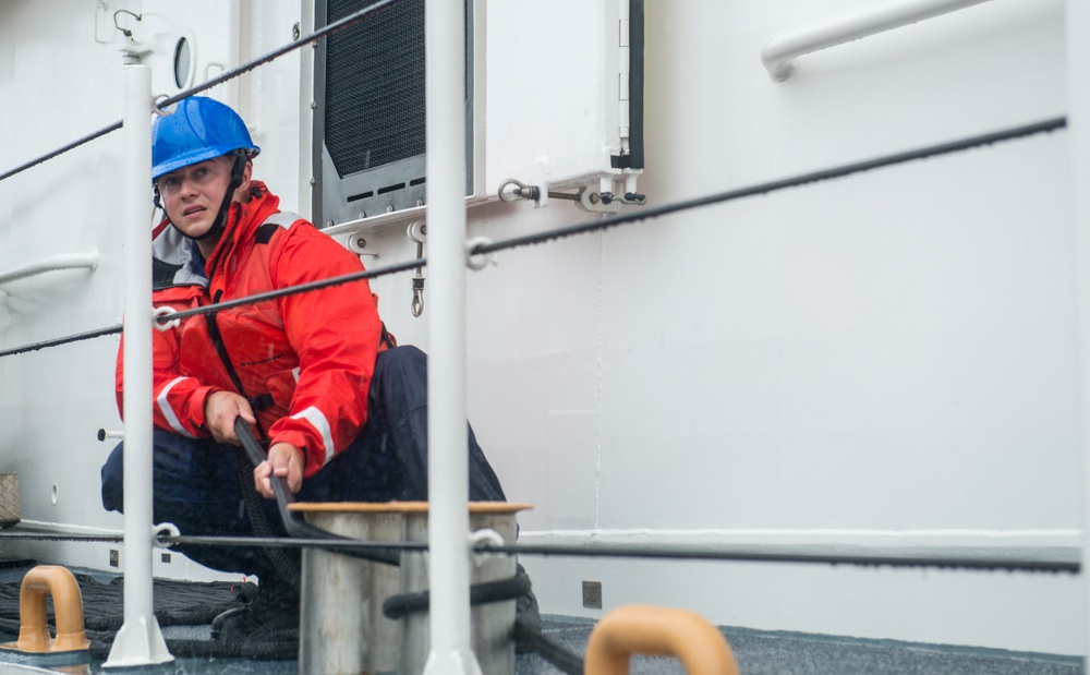 Coast Guard crew member secures a line to set of bitts