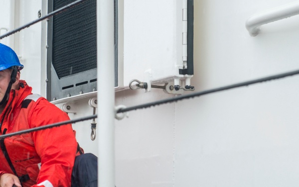 Coast Guard crew member secures a line to set of bitts