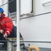 Coast Guard crew member secures a line to set of bitts