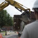 Airmen help guide heavy equipment operator as they restore buildings at the West Virginia Schools for the Deaf and the Blind