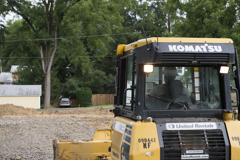 Airmen operates a bulldozer to spread road mix for parking lot