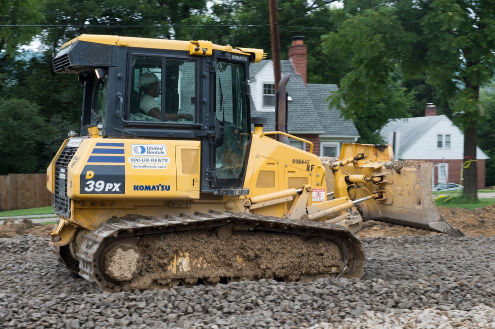 Airmen operates a bulldozer to build new parking lot for school