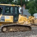 Airmen operates a bulldozer to build new parking lot for school