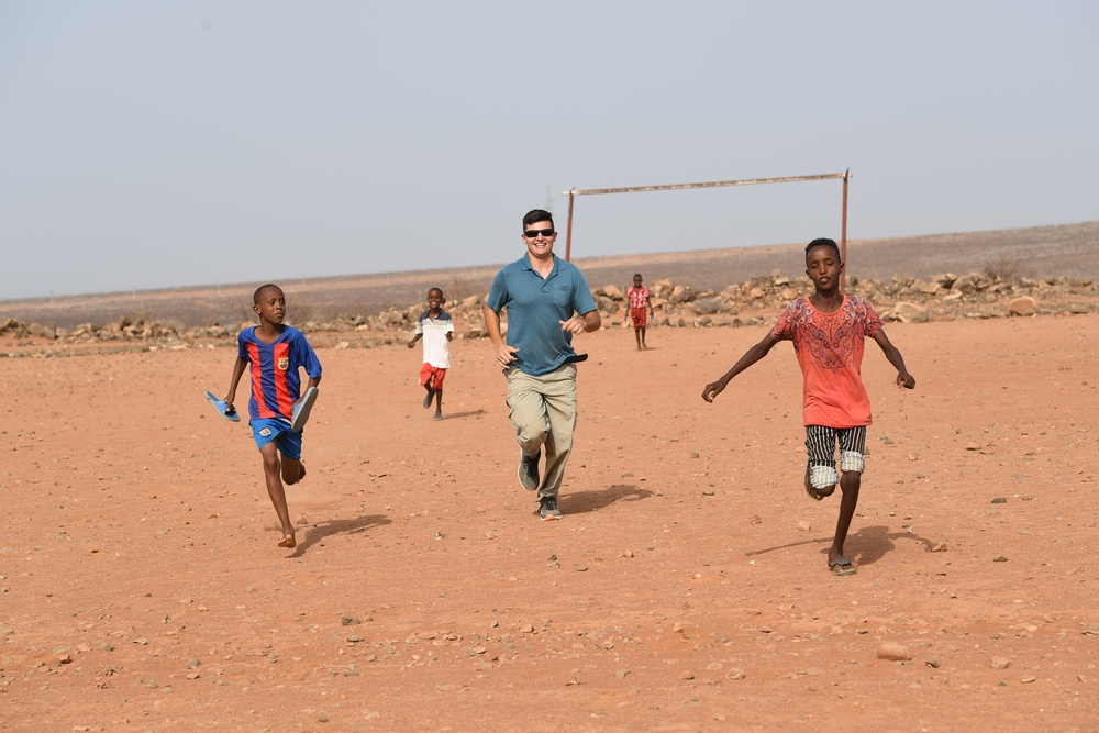 U.S. service members play soccer with local children