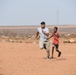U.S. service members play soccer with local children