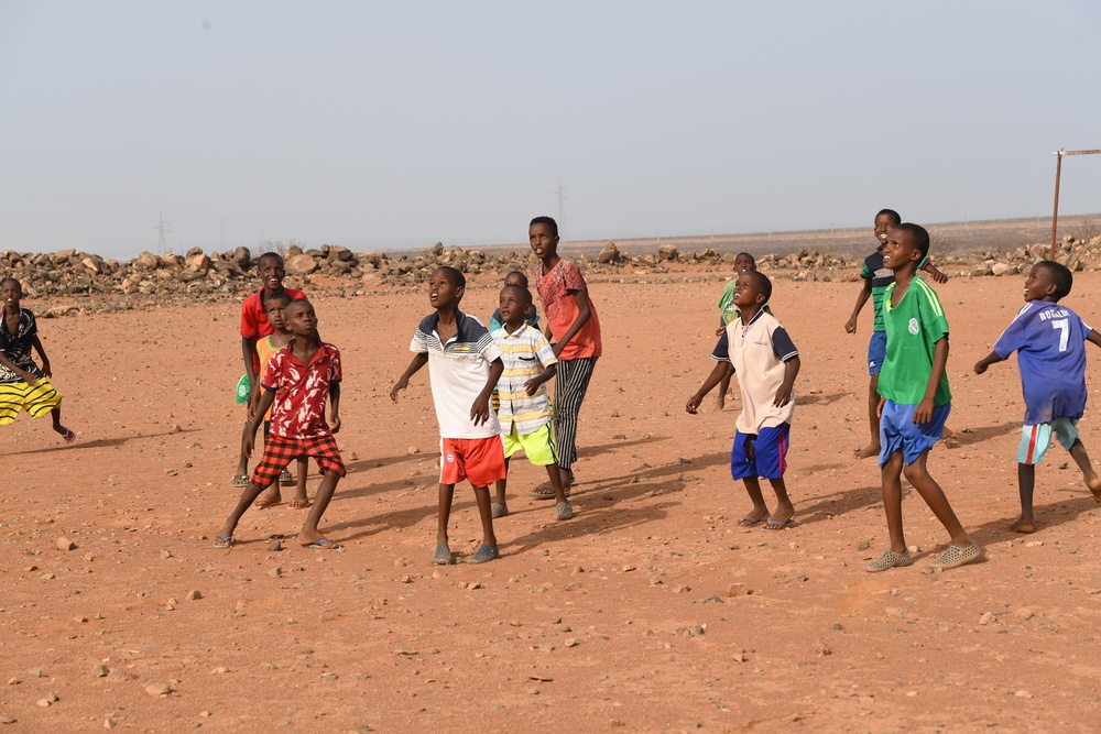 U.S. service members play soccer with local children