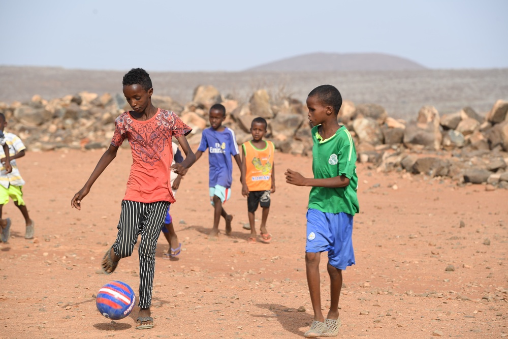 U.S. service members play soccer with local children