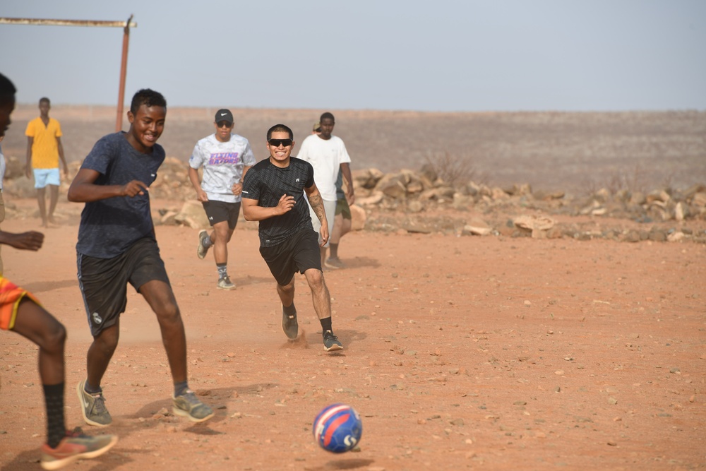 U.S. service members play soccer with local children
