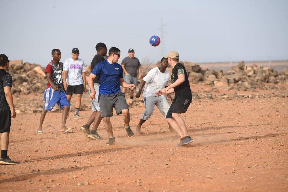 U.S. service members play soccer with local children