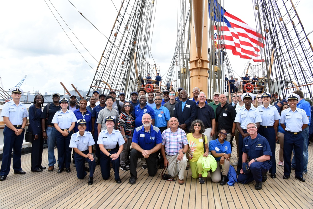 The Coast Guard Cutter Barque Eagle's crew gather with local community and industry members for a group photo