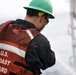 A Coast Guard Cutter Fir crewmember power-washes marine growth off the bottom of a whistle buoy in Panama