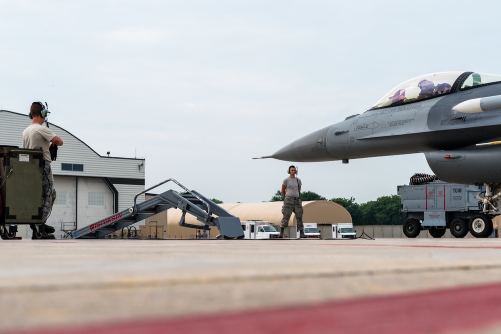 Crew chiefs marshal an F-16 Fighting Falcon