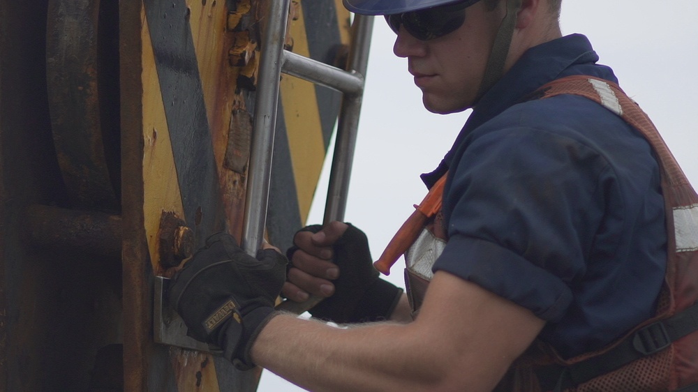 A Coast Guard Cutter Fir guardsman prepares to lift a whistle buoy out of the Port of Panama