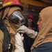 Culinary Specialist 2nd Class Allyson Gonzales (right), from San Diego, assists a Sailor dressing out in firefighting gear on the Ticonderoga-class guided-missile cruiser USS Antietam (CG 54) during a general quarters training exercise