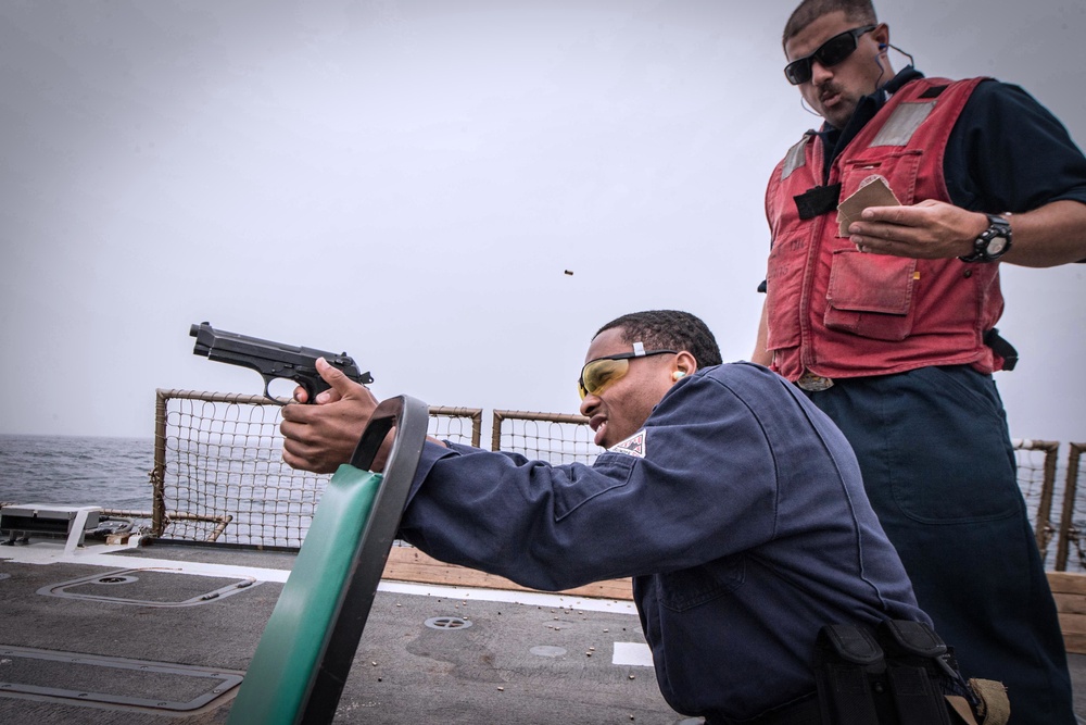 Sailors shoot guns for pistol qualification on USS Jason Dunham