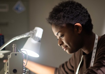 Aviation Machinist's Mate Airman Celine Dupont, from Port Au Prince, Haiti, sews a rank insignia on a uniform in the tailor shop aboard the Nimitz-class aircraft carrier USS John C. Stennis (CVN 74).