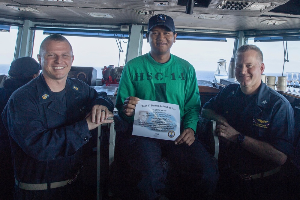 Aviation Electrician’s Mate 3rd Class Kyaw Htat, center, from Baltimore, poses for a photograph as the Sailor of the Day